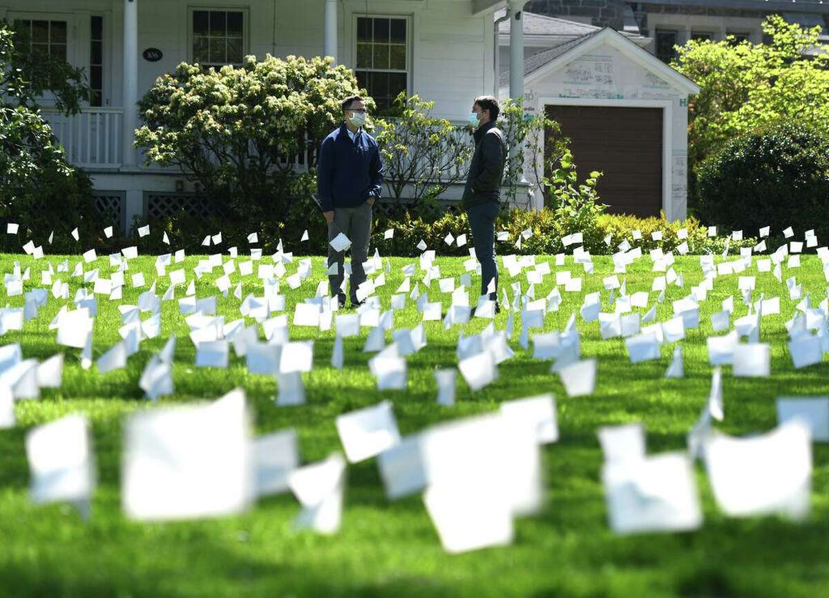 The Rev. Patrick Collins, left, and U.S. Rep. Jim Himes, D-Conn., look upon flags in memory of the Connecticut lives lost from coronavirus at First Congregational Church of Greenwich in Old Greenwich, Conn. Tuesday, May 12, 2020.