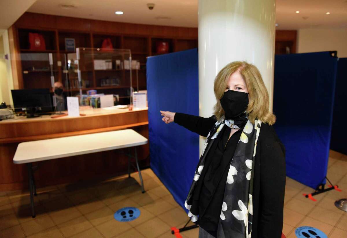 Library President Alice Knapp shows the plexiglass windows and line dividers at the check-out counter at Fergsuon Library in Stamford, Conn. Thursday, Feb. 4, 2021. Outside agencies got a cash infusion from the city's planning board in this year's budget recommendation, and the Ferguson Library was one of the organizations to reap the benefit.