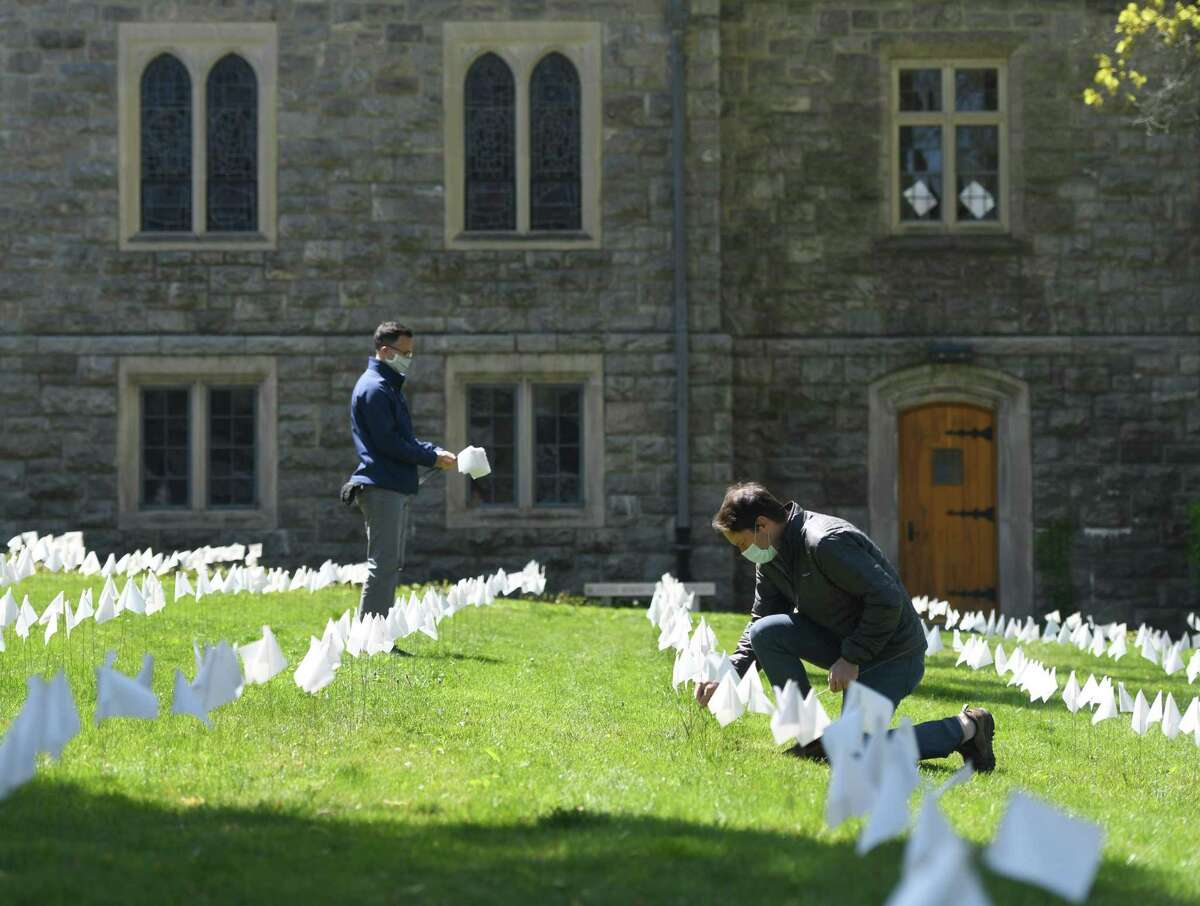 The Rev. Patrick Collins, left, and U.S. Rep. Jim Himes, D-Conn., place flags in memory of the Connecticut lives lost from coronavirus at First Congregational Church of Greenwich in Old Greenwich, Conn. Tuesday, May 12, 2020. The Rev. Collins placed flags in memory of 41 lives lost on Tuesday, bringing the total to more than 3,000.