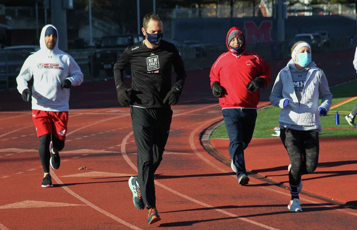 Brien McMahon High School football coach Jeff Queiroga, left, takes part in a 48 miles in 48 hours challenge to raise money for charity at the school in Norwalk, Conn., on Friday Mar. 5, 2021. Joining him in the run is guidence counselor John Castelluzzo, McMahon staffer Chistopher Scalise and teacher Eileen Kinne.