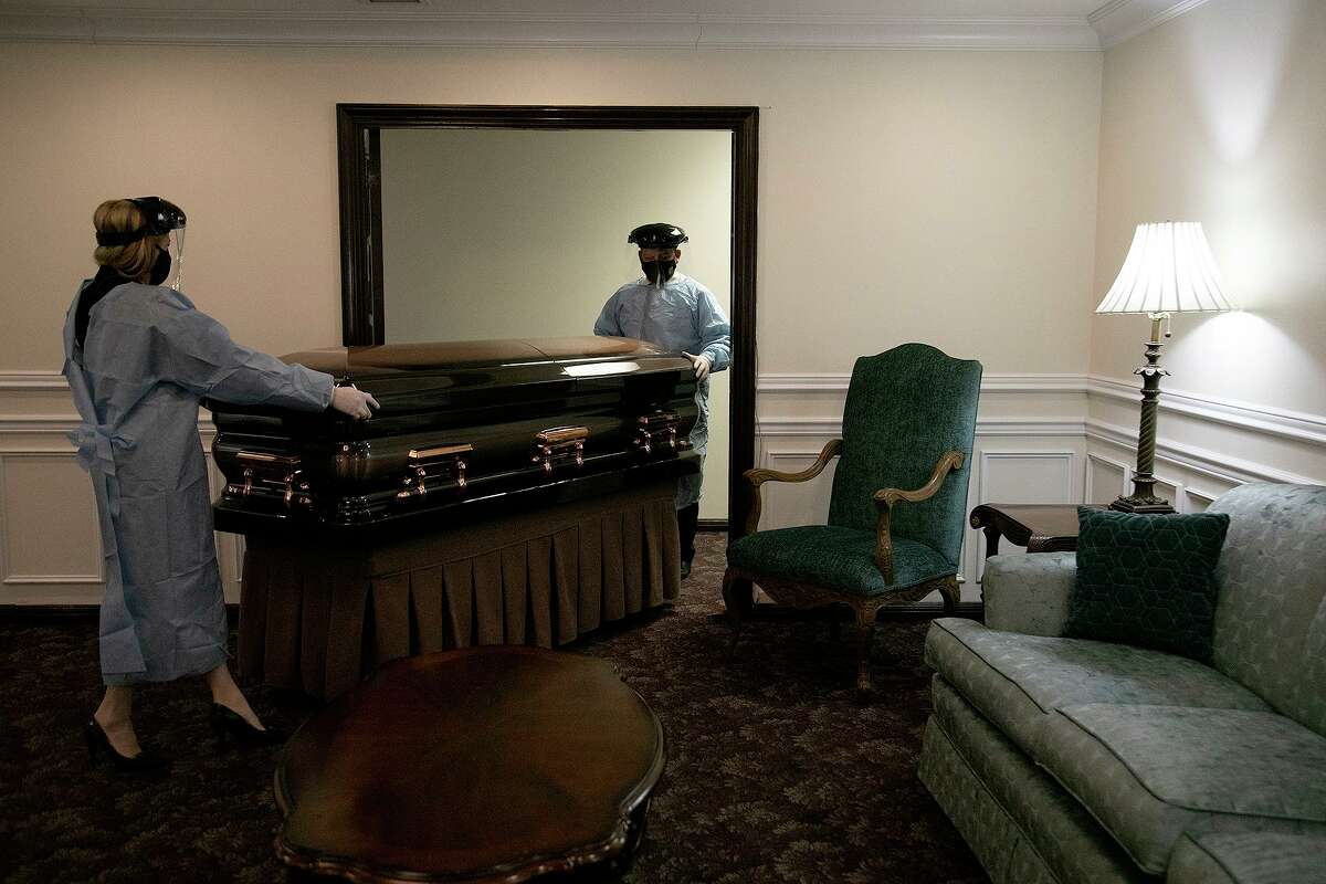 Kristin Tips, president and funeral director of Mission Park Funeral Chapels and Cemeteries, and funeral director Tim Puchner place a deceased person in a visitation suite at Mission Park Funeral Chapels Cherry Ridge in San Antonio on Feb. 25, 2021.