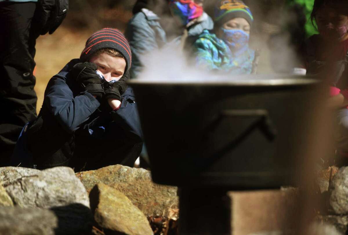 Lucas Peck, 7, of Monroe, watches a pot of maple sap boil over an open fire during a maple sugaring demonstration at the Nature and Arts Center in Trumbull, Conn. on Sunday, March 07, 2021.