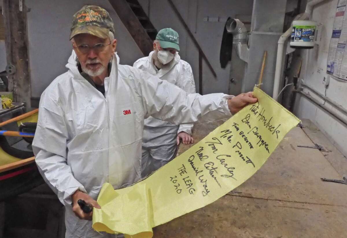 Peter Hornbeck of Hornbeck Boats holds up the piece of fabric signed by members of the LEAG who contributed to the building of a one-of-a-kind Hornbeck boat, which will be raffled by the Adirondack Center for Loon Conservation. The fabric was installed into the boat's hull.