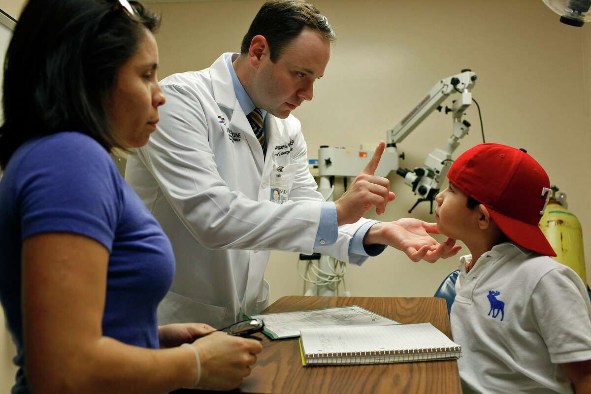 Dr. Justin B. Williams, associate director of the Center of Emergency Medicine in San Antonio, left, examines Reynaldo Rodriguez, 7, who came in for treatment of conjunctivitis (pink eye) while his mother, Jenny Hernandez, left, watches in the emergency room at University Hospital.
