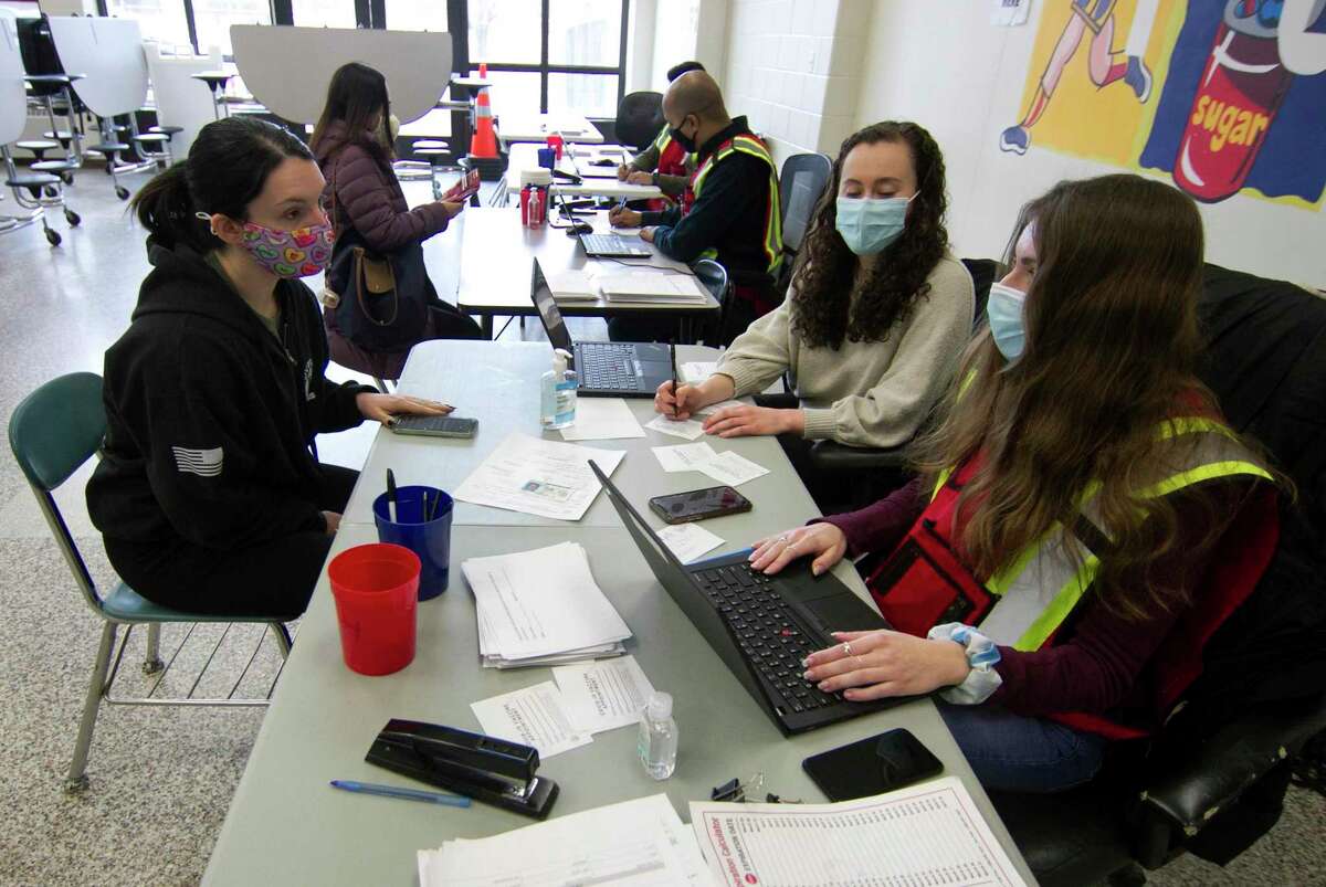 Danbury teacher Lauren Brown, left, checks in with staff to receive her Moderna COVID-19 vaccination at a clinic set up at Rogers Park Middle School in Danbury, Conn., on Saturday Mar. 6, 2021. Over 900 teachers and staff received the Moderna vaccine during the two-day clinic.