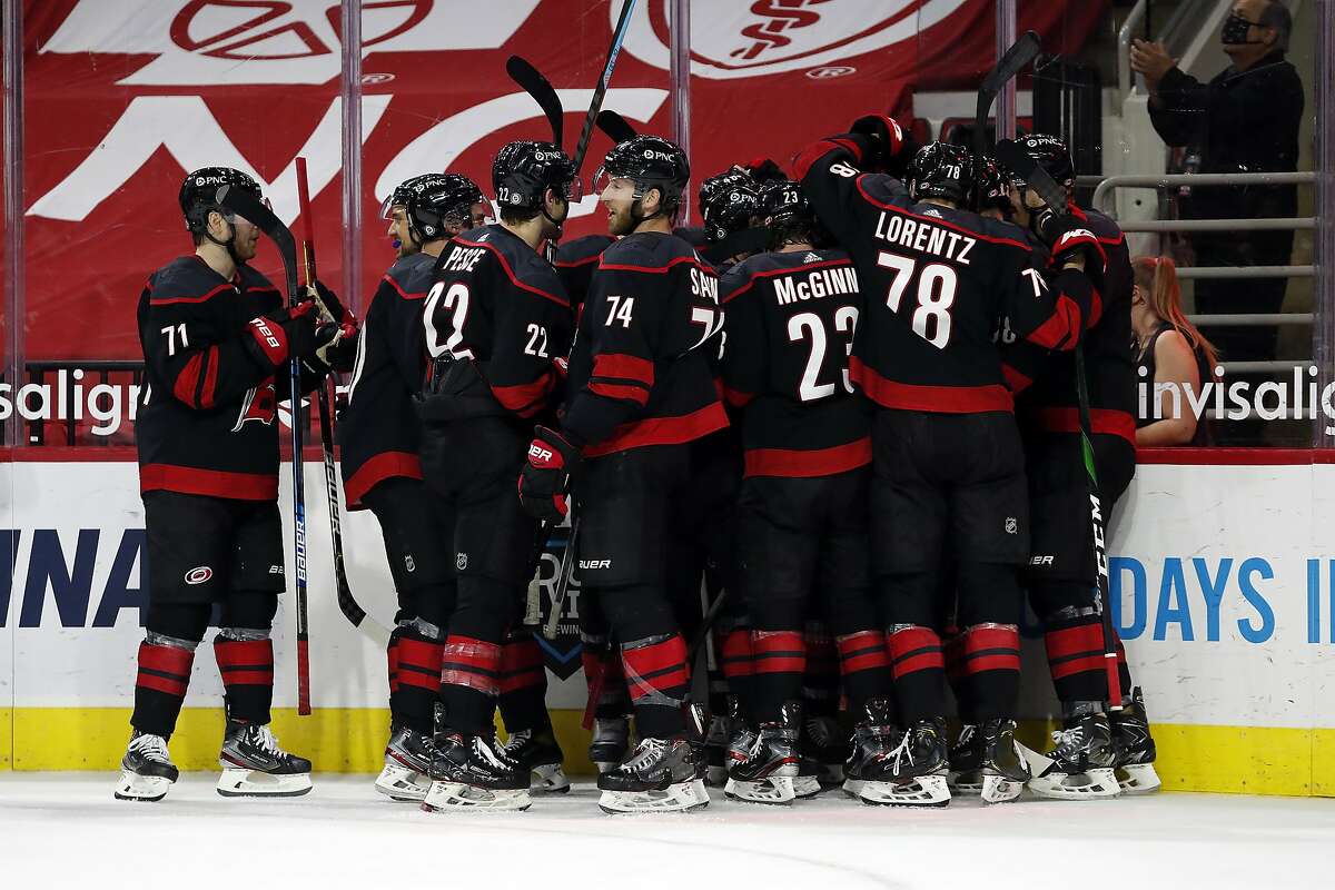 The Carolina Hurricanes celebrate with Jordan Staal after his overtime goal against the Nashville Predators in an NHL hockey game in Raleigh, N.C., Tuesday, March 9, 2021. (AP Photo/Karl B DeBlaker)