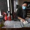 Kobe Trongjittham sanitizes menus at Chaba Thai. The restaurant reopened for in-person dining just a month ago and will continue to require masks to be worn when not seated at a table. Photo made Wednesday, March 10, 2021 Kim Brent/The Enterprise