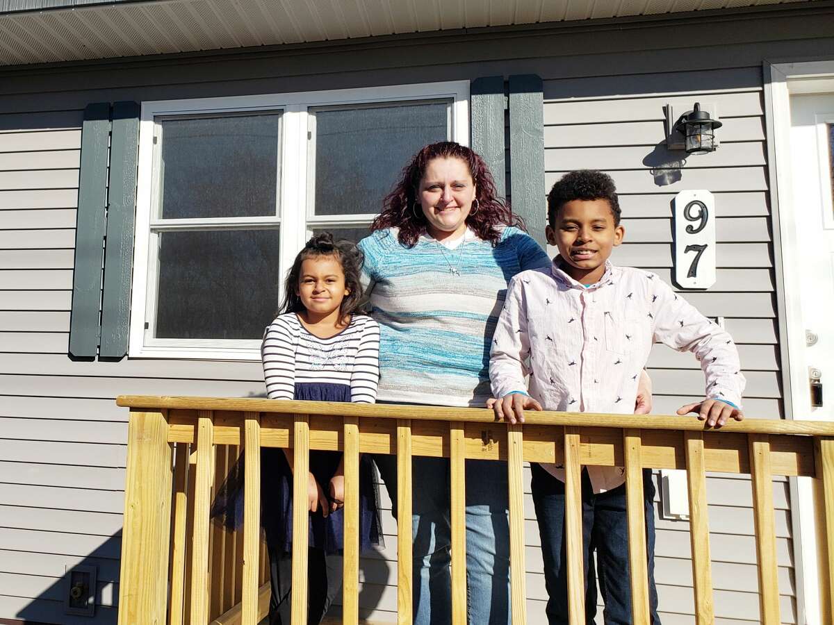 FILE — (From left) Jessica Allen, Crystal Buck and James Allen stand on the porch of their new home on Fourth Street in Eastlake after several years of work with the Manistee County Habitat for Humanity.