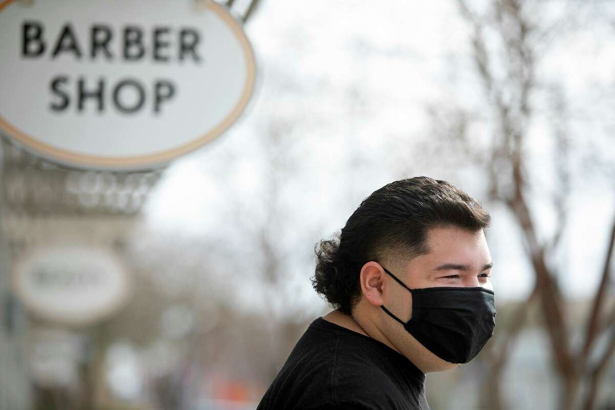 Cristian Muñiz's stands outside Pinstripes Classic Barber Shop after his haircut in San Antonio Thursday.