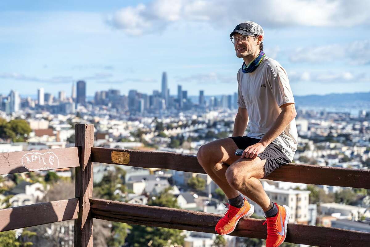 Ultrarunner Luke Wicker rests with a view of downtown San Francisco, during his March 6, 2021, run that covered 76 of the city's peaks. He ran 65 miles and climbed more than 10,000 feet.