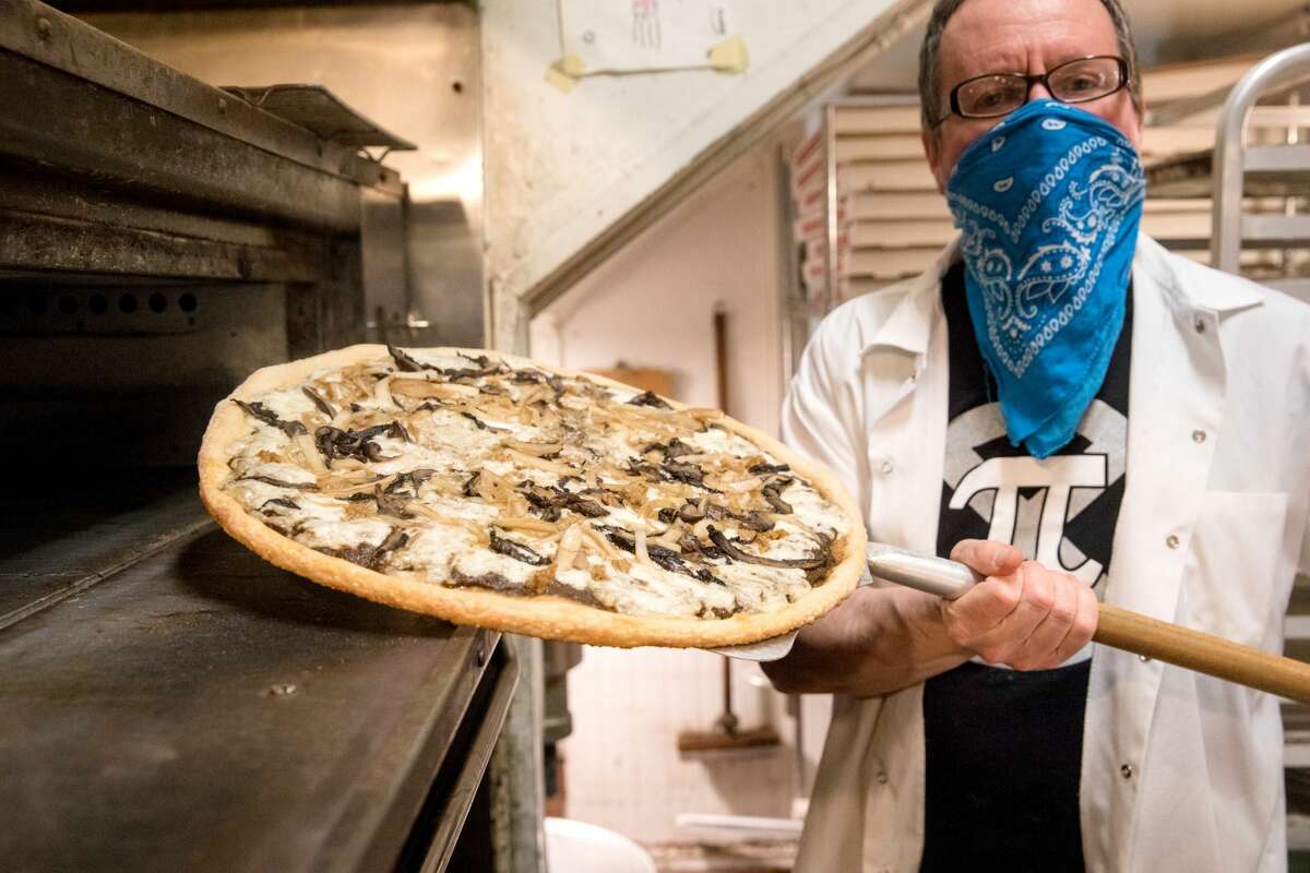 Co-owner Rich Rosen takes one of Pi Bar's signature mushroom pizzas out of the oven at his restaurant in San Francisco on March 12, 2021.