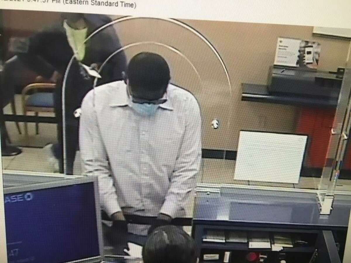 Surveillance camera footage shows a robbery suspect at the Main Street Chase Bank approaching a customer service counter, displaying a note and leaving with a black tote bag.