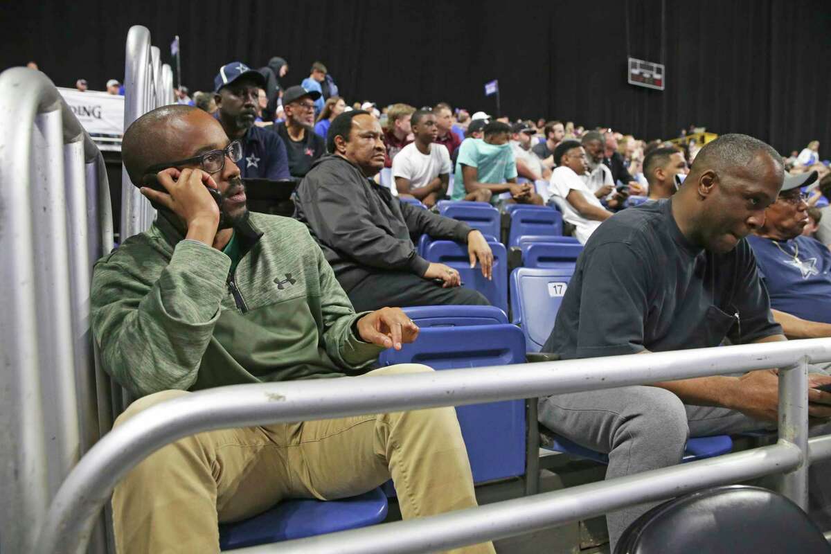 Bobby Clemons, Jr., left, from Austin makes arrangements for his return trip home just before the class 3A state semifinal boys basketball game between Cole and Peaster at the Alamodome on Feb. 12, 2020. Mark Ervin, right, from Columbus, Ohio already had made plans to go home in response to the suspension of games at the UIL.