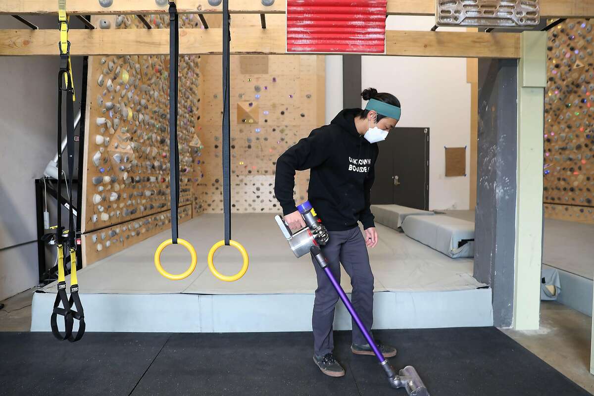 Alex Chuong, owner and operator of Oaktown Boulders in Oakland, vacuums as the climbing gym prepares for reopening after Alameda County was moved to the red tier.