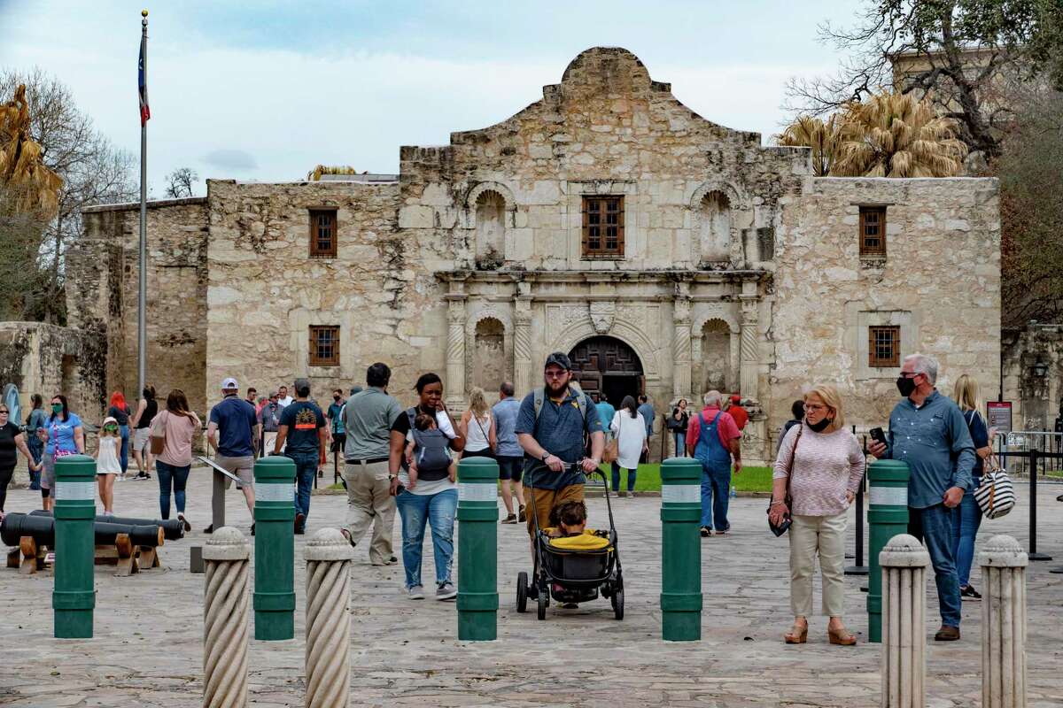 Some people wear masks and some do not as they tour the Alamo on Wednesday, March 10, 2021.