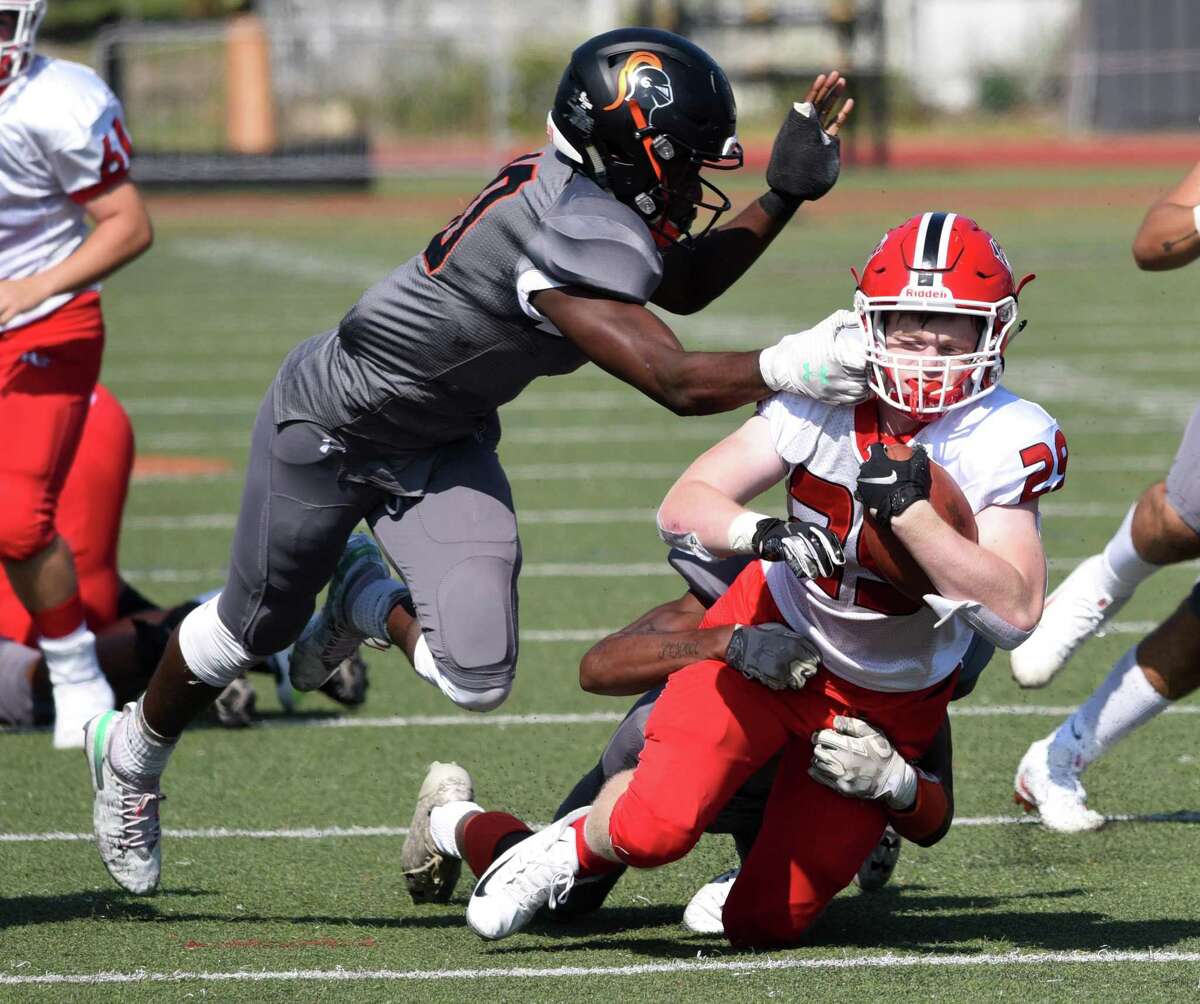 Stamford's Courtney Lewis and Daniel Simms, left, tackle New Canaan's John Wise at Boyle Stadium in Stamford in 2019. Simms has transferred to St. Thomas More and will continue his playing as a post graduate in the fall.