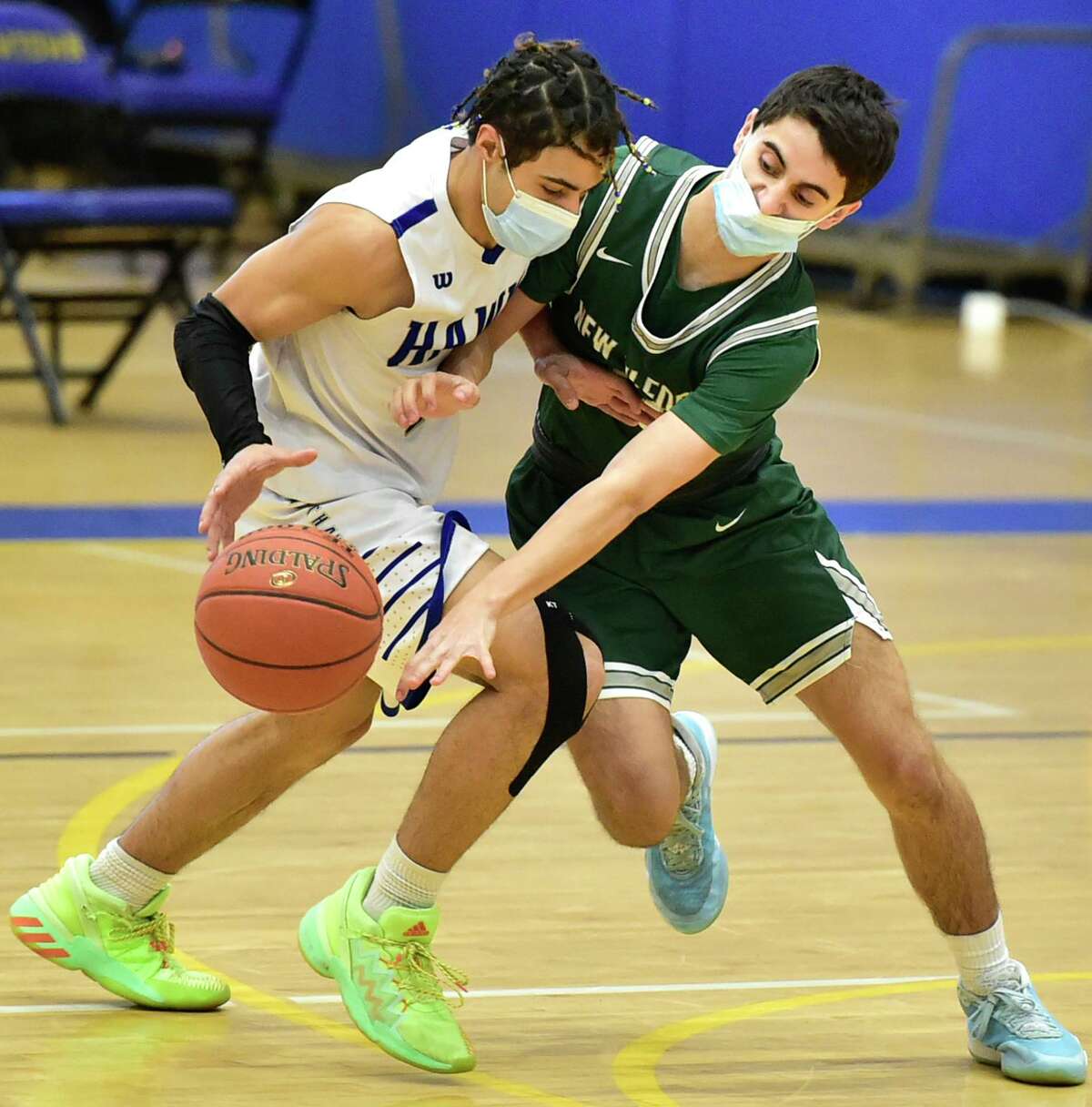 Newtown, Connecticut - Monday, March 15, 2021: Joseph McRay of Newtown left, tries to protect the ball against the defense of Stephen Sampinato of New Milford H.S. during the first quarter of basketball Monday at Newtown High School.