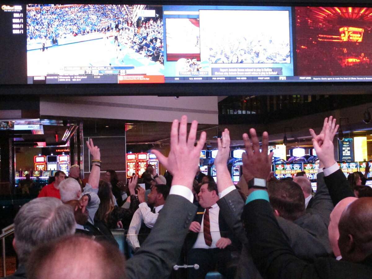 Fans watch college basketball in the sports betting facility at the Tropicana casino in Atlantic City, N.J. on March 8, 2019, the last year the March Madness tournament was held. The American Gaming Association predicts 47 million people will bet on this year's tournament, about the same as two years ago. But 8% fewer plan to fill out brackets pools because many offices remain closed due to the coronavirus pandemic. (AP Photo/Wayne Parry)