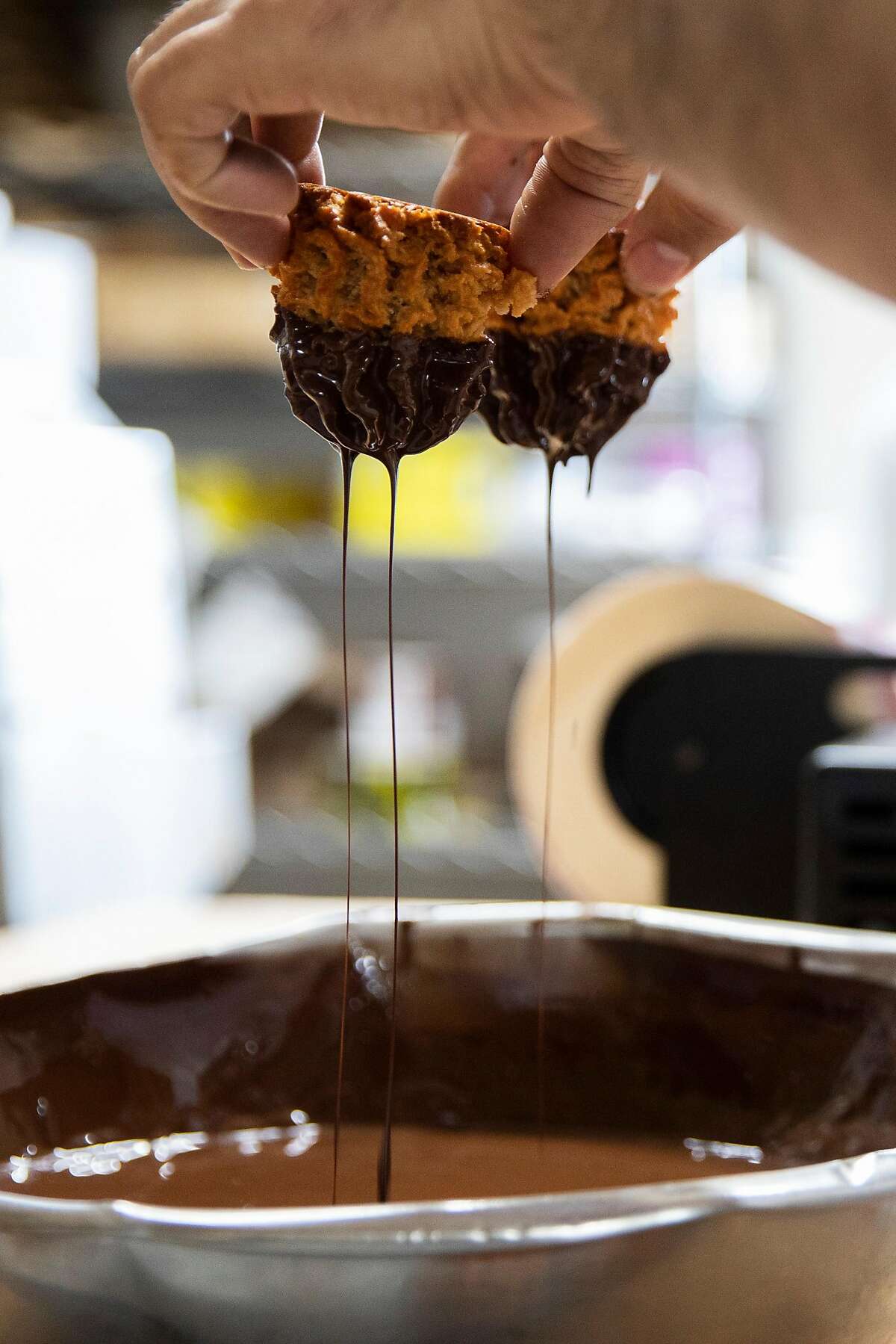 A Grand Bakery employee dips freshly baked macaroons in melted chocolate while preparing them for sale at Grand Bakery in Oakland, Calif. Monday, March 15, 2021. The Passover recipe featured on Grand Bakery's famous macaroons takes 5 hours to make.The Passover recipe feature on Grand Bakery's famous macaroons takes 5 hours to make.