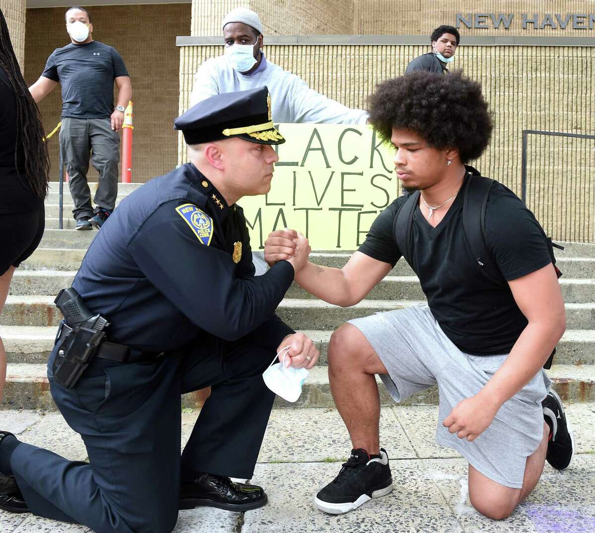 New Haven Police Chief Otoniel Reyes (left) takes a knee to the ground with Wilbur Cross junior Jabez Cubiz, 18, in front of the New Haven Police Department after the chief met with protesters on June 3, 2020 in the aftermath of the death of George Floyd at the hands of Minneapolis Police.