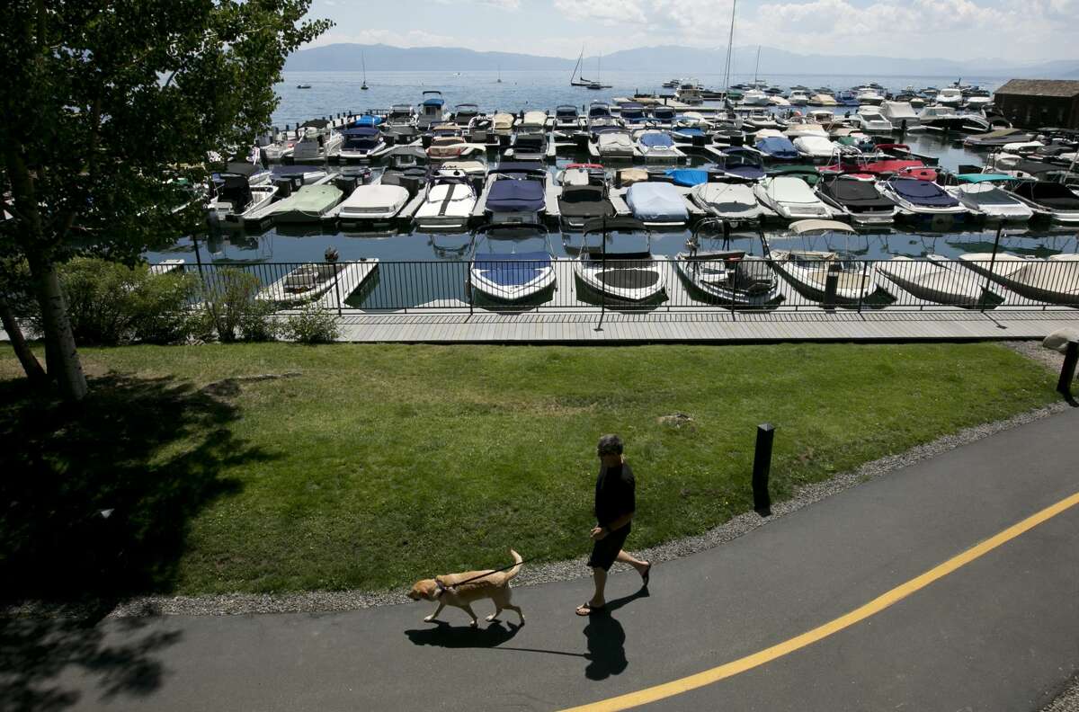 A pedestrian and a dog walk past the marina in Tahoe City in 2017. Businesses in North Tahoe are reopening, as an effort to organize a new district solidifies.