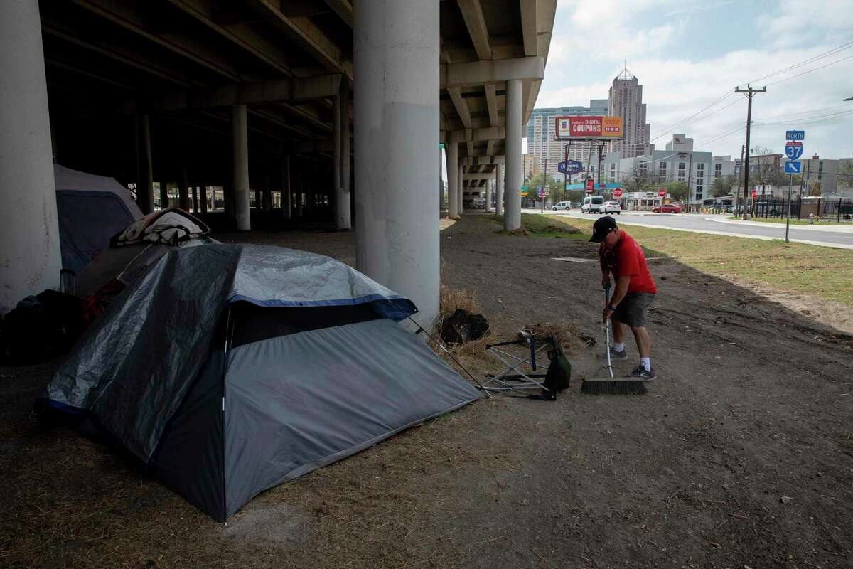 John Mellow sweeps the area around his friends’ tents under the Interstate 37 overpass near McCullough, east of downtown San Antonio, on March 16, 2021. Mellow says he does so to keep things as clean as possible and make living conditions just a little better. Word had spread that the encampment was to be removed soon, as it had been in early February.