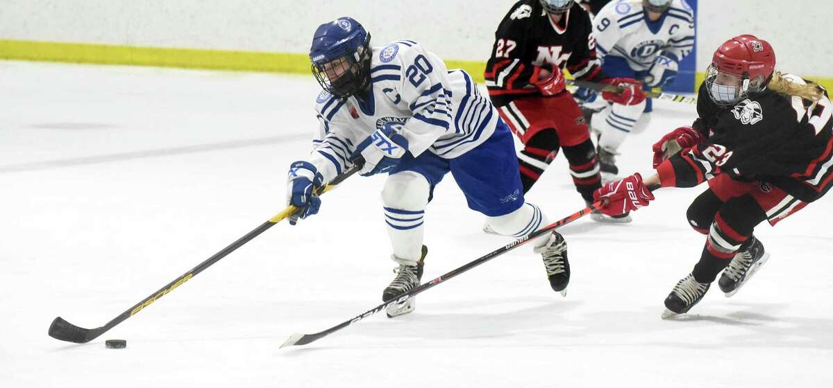 Darien's Nelle Kniffin (20) plays the puck as New Canaan's Lexie Tully (23) defends during a girls ice hockey game at the Darien Ice House on Saturday, March 6, 2021.
