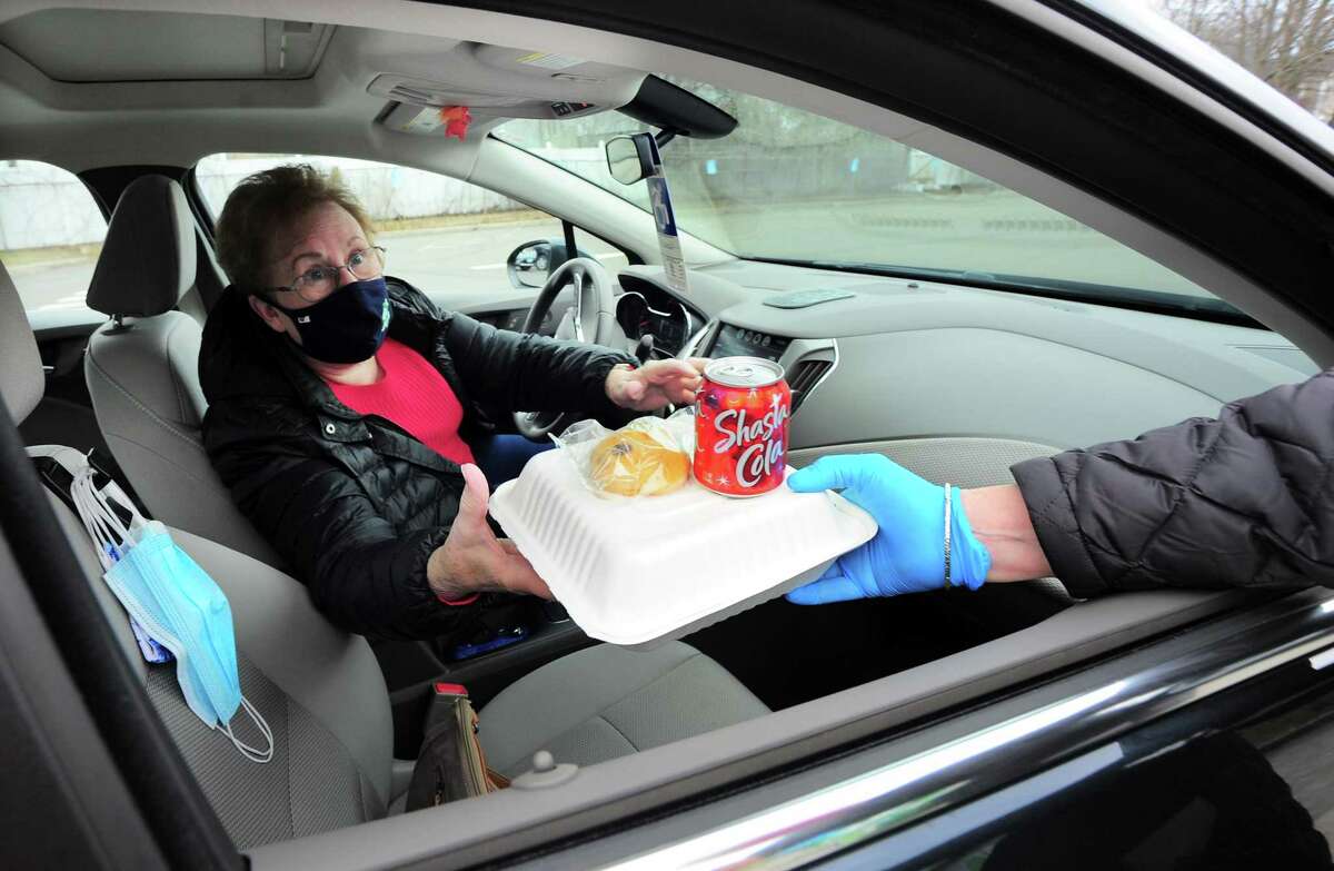 Carol Freunscht receives a free lunch of corned beef and cabbage, which were boxed up and handed out for a special St. Patrick's Day drive-thru luncheon at The Bigelow Center for Senior Activities in Fairfield, Conn., on Tuesday Mar. 16, 2021.