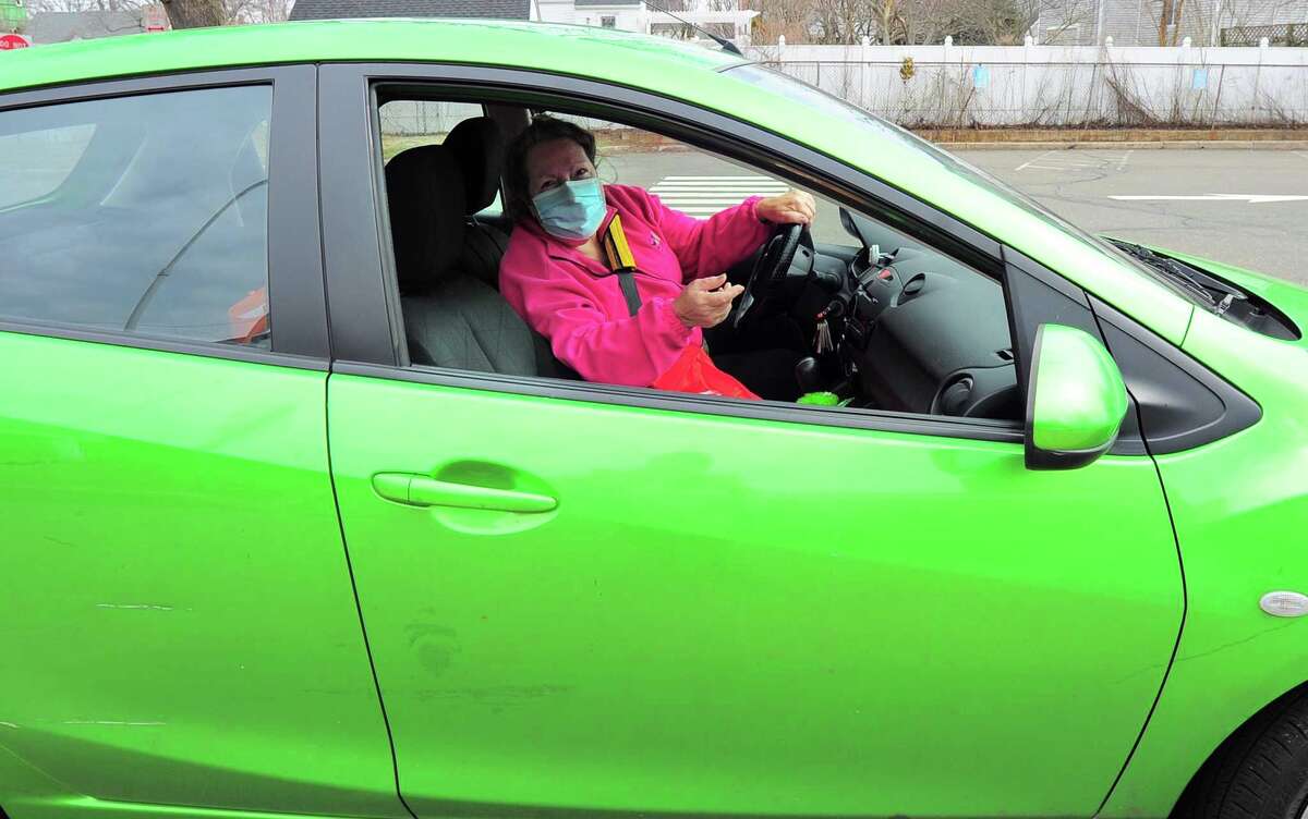 Gale Haskell, who drove up in a green Toyota, receives her lunch of corned beef and cabbage which were boxed up and handed out for a special St. Patrick's Day drive-thru luncheon at The Bigelow Center for Senior Activities in Fairfield, Conn., on Tuesday Mar. 16, 2021.