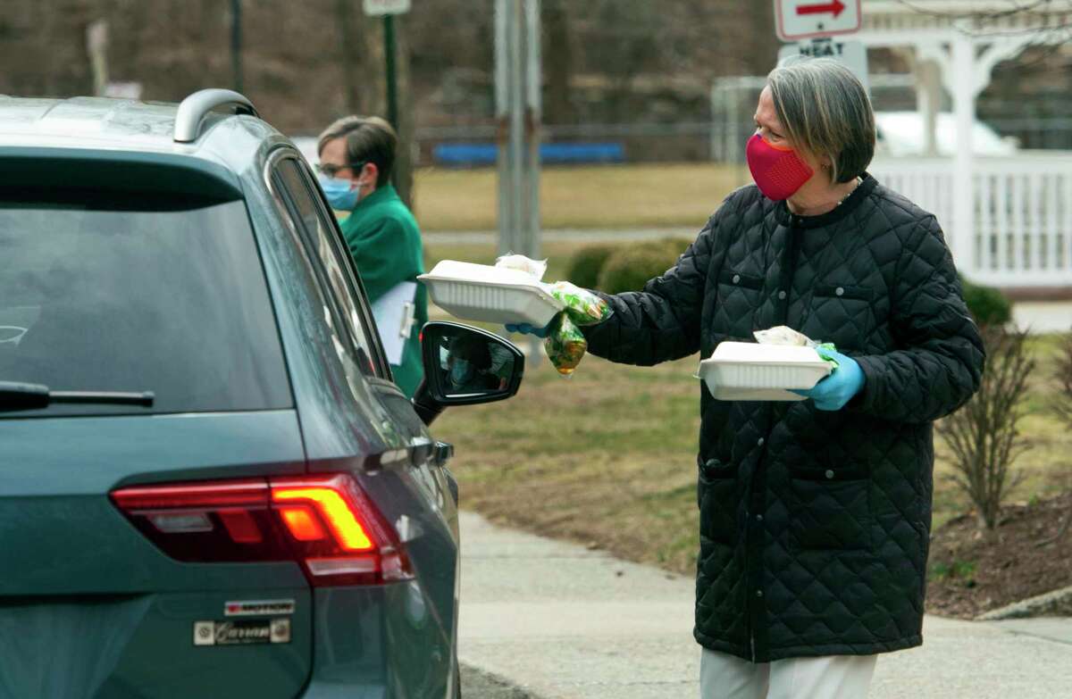 Bigelow Center for Senior Activities Social Services Director Julie DeMarco hands out free lunches of corned beef and cabbage, which were boxed up and handed out for a special St. Patrick's Day drive-thru luncheon at the center in Fairfield, Conn., on Tuesday Mar. 16, 2021.