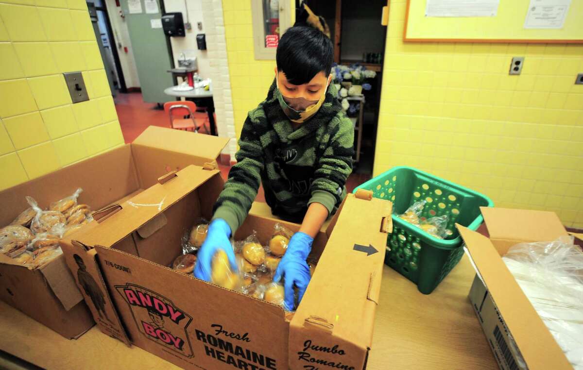 Alexis Atemiz, 10, helps to prepare lunches of corned beef and cabbage, which were boxed up and handed out for a special St. Patrick's Day drive-thru luncheon at The Bigelow Center for Senior Activities in Fairfield, Conn., on Tuesday Mar. 16, 2021.