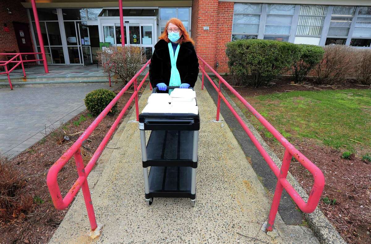 Bigelow Center for Senior Activities staff secretary Nora Cooper brings out out free lunches of corned beef and cabbage, which were boxed up and handed out for a special St. Patrick's Day drive-thru luncheon at the center in Fairfield, Conn., on Tuesday Mar. 16, 2021.