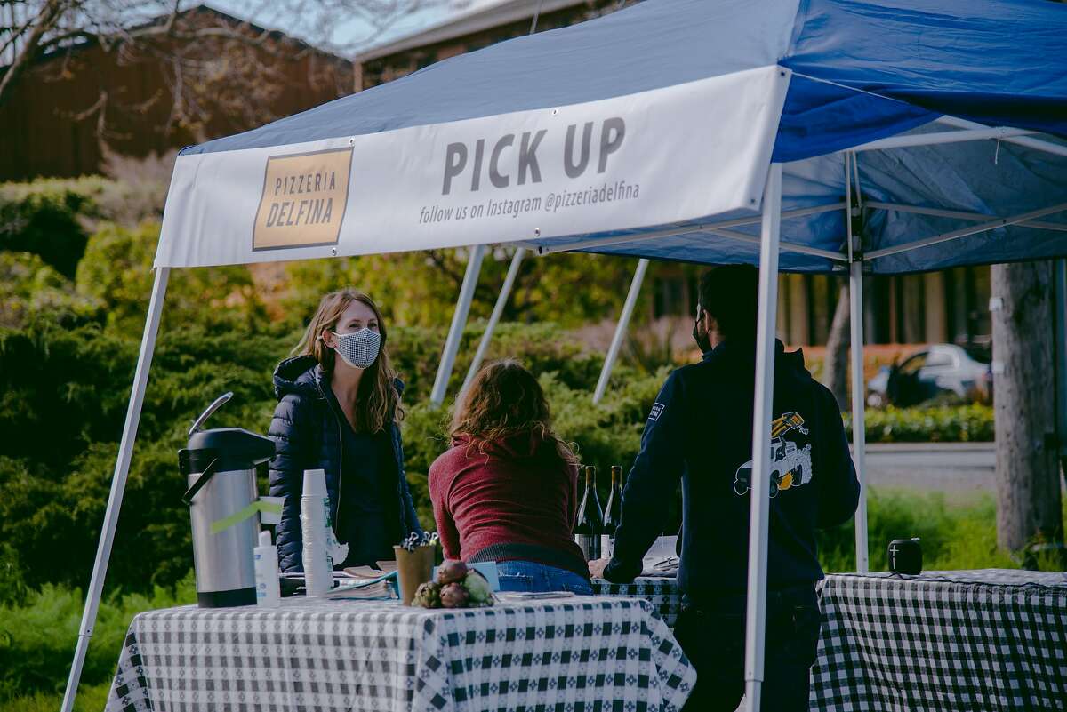 A customer picks up an online order from Pizzaria Delfina’s SF2BAY pop-up in Mill Valley, Calif., on Saturday, March 13, 2021. SF2BAY is a food delivery service founded during the COVID-19 pandemic that brings beloved San Francisco restaurants to other regions in the Bay Area.