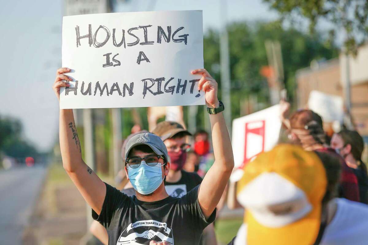 "Toby" holds a sign with other demonstrators during a protest regarding evictions going on at the court, 6000 Chimney Rock Road, Friday, Aug. 21, 2020, in Houston.