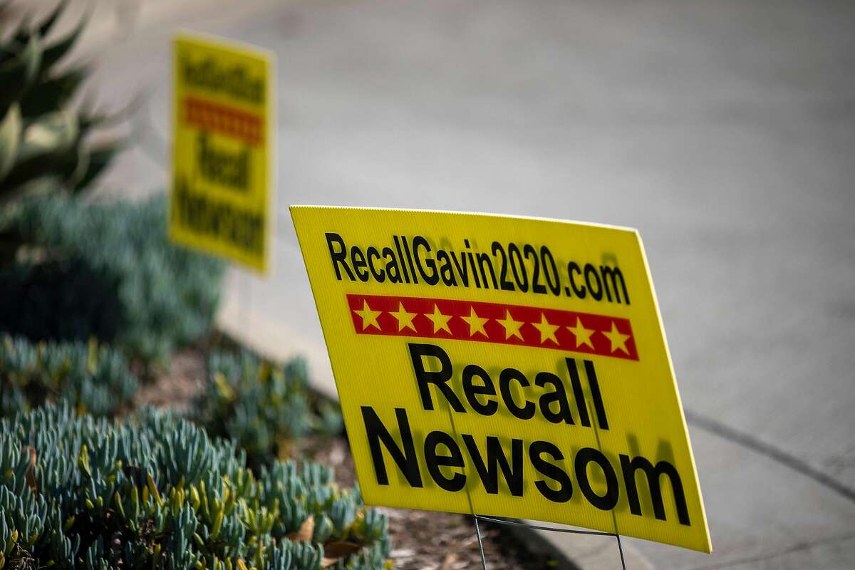 Signage is seen near a booth where conservative activists gather signatures in a recall effort against Gov. Gavin Newsom near Pasadena City Hall on Feb. 28, 2021.