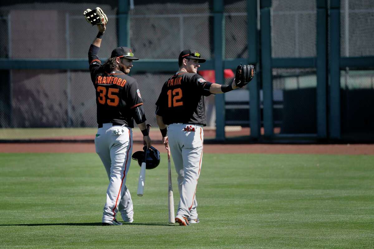 Infielders Brandon Crawford, 35 (left) and Joe Panik, 12 wave to fans in the stands during the San Francisco Giants spring training workouts at Scottsdale Stadium on Wed. February 24, 2016, in Scottsdale, Arizona