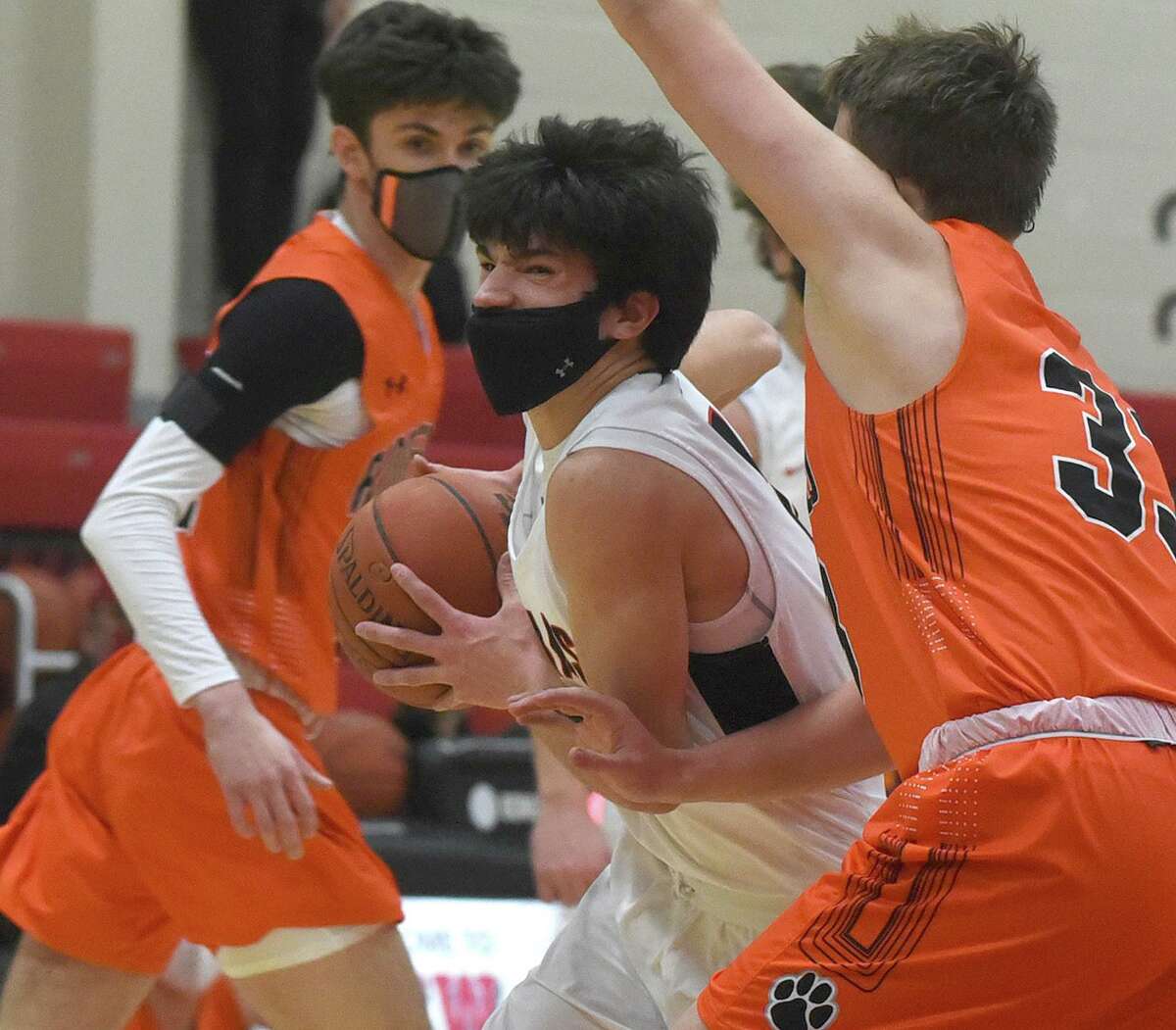 New Canaan's Will Bozzella (14) drives against Ridgefield's Dylan Veillette (33) during a boys basketball game at New Canaan High School on Wednesday, March 3, 2021.