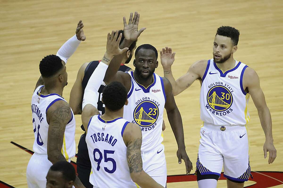 Golden State Warriors' Draymond Green (23) high-fives Kent Bazemore, left, Stephen Curry (30) and Juan Toscano-Anderson (95) during the first quarter against the Houston Rockets in an NBA basketball game Wednesday, March 17, 2021, in Houston. (Carmen Mandato/Pool Photo via AP)