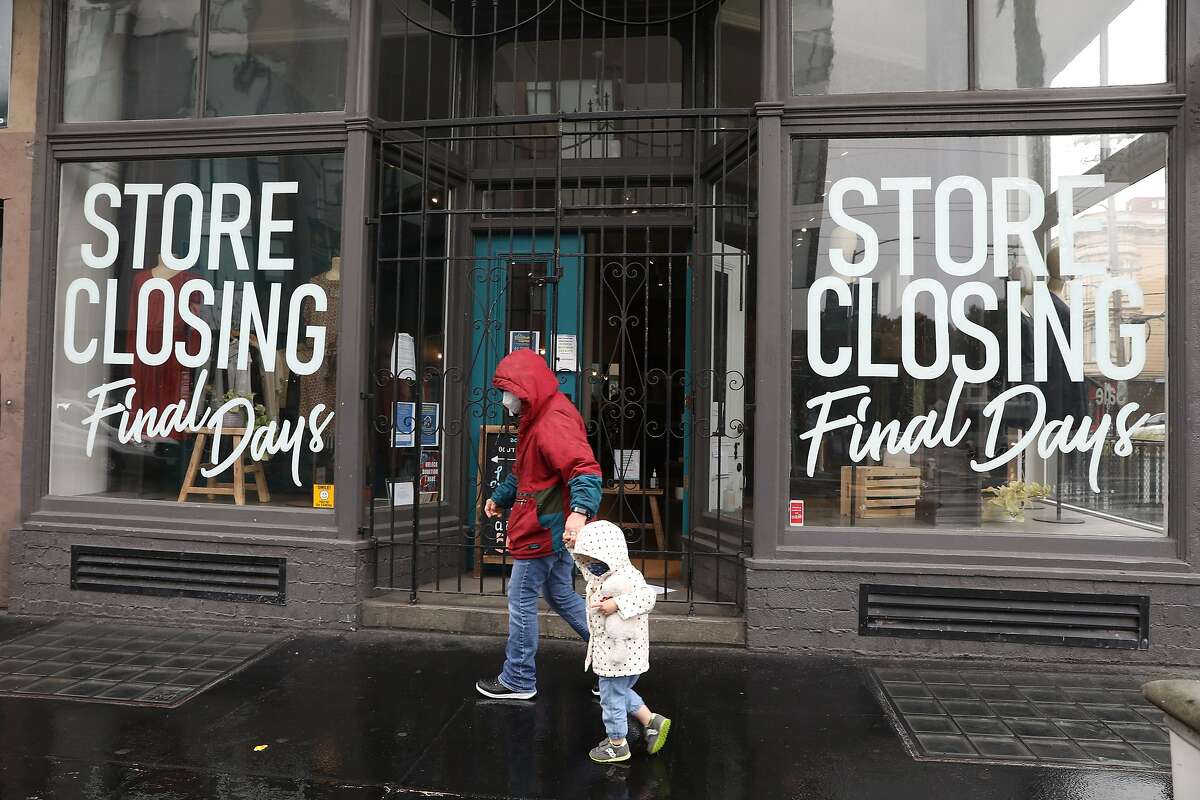 Maureen Verkamp holds the hand of grandaughter Isla Verkamp, 2, as they walk in the rain on Hayes Street past Acote in San Francisco. Acote, a French clothing boutique in Hayes Valley, closed permanently on March 21.