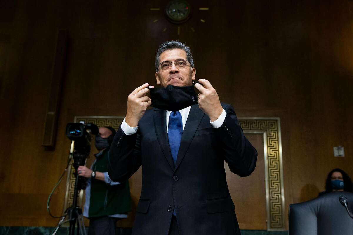 Xavier Becerra puts on a mask at his confirmation hearing for secretary of Health and Human Services in February.