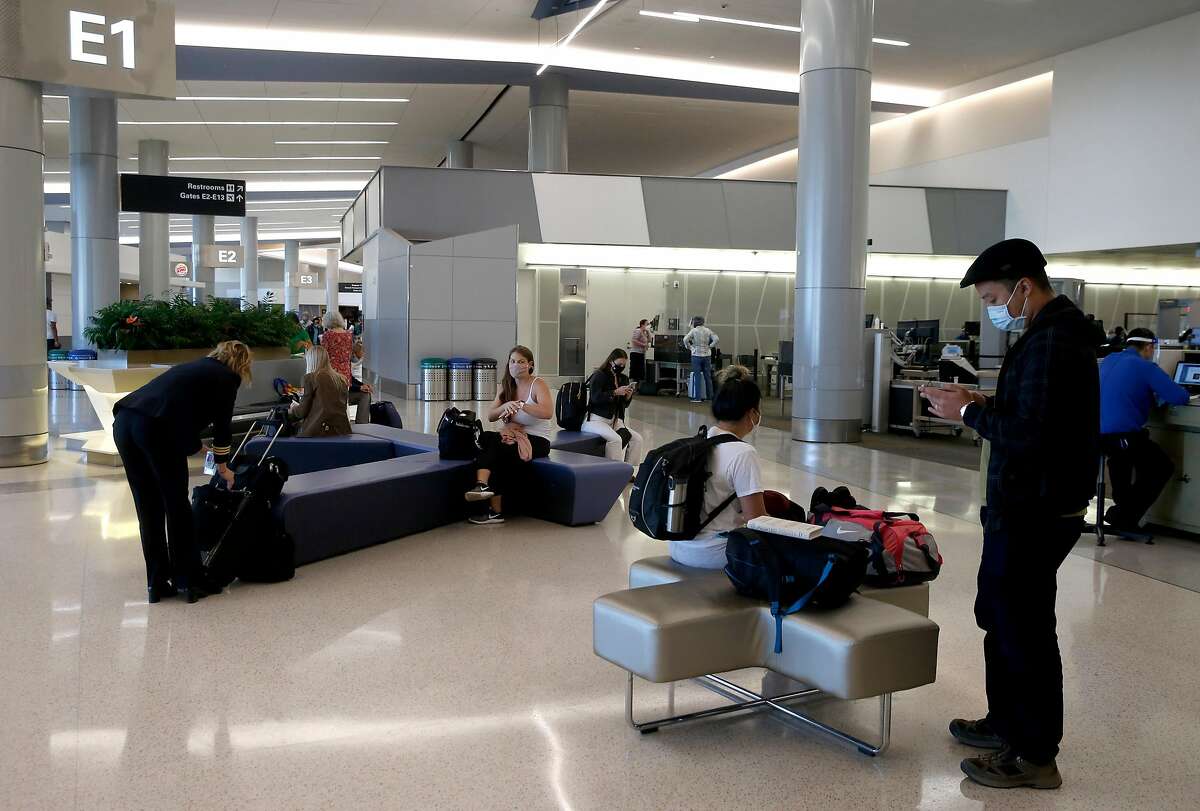 Travelers organize carry-on items after security screening at San Francisco International Airport in October.