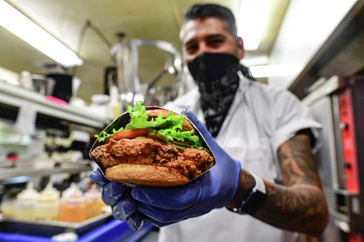 Chef Adrian Cruz displays a Miss Mazy's Amazin’ Chicken fried chicken sandwich that he prepared at Ghost Kitchens SA.