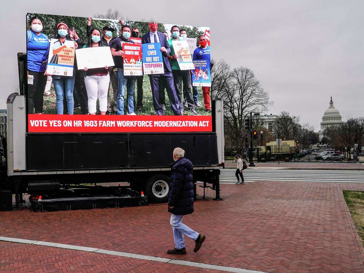 WASHINGTON, DC - MARCH 17: A man walks past an installation erected outside of Union Station demanding a "yes" vote on the American Dream and Promise Act and the Farm Workforce Modernization Act for the House and Senate on March 17, 2021 in Washington, DC.