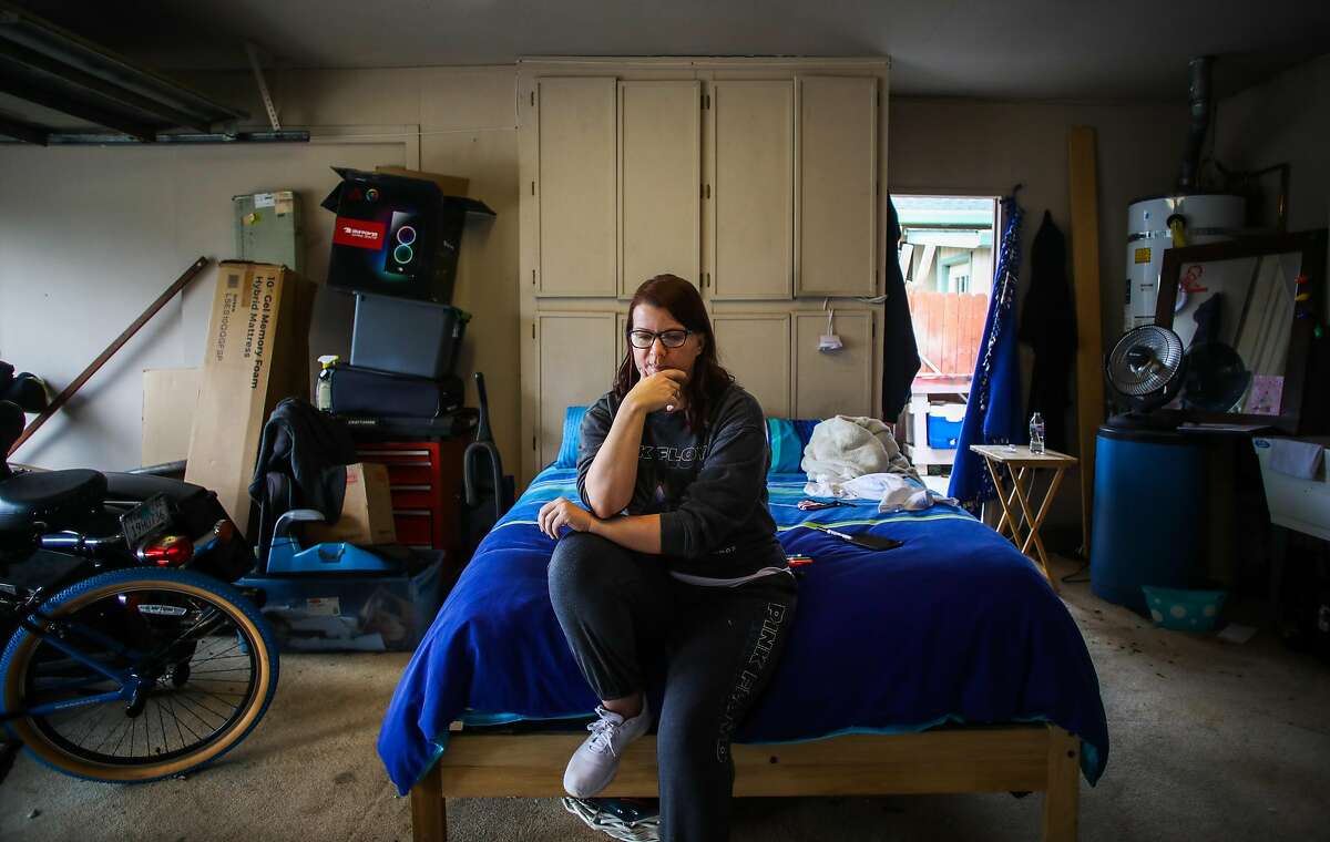 Carie Mathis, 51, sits on her bed inside her parents' garage on Tuesday, March 9, 2021, in Vacaville, Calif. Mathis is living in her parents' garage because her housecleaning business collapsed with the pandemic. Mathis has not received any unemployment benefits since December, despite hours on the phone. "I want out of this garage so bad," Mathis said. "I want things to return back to normal."