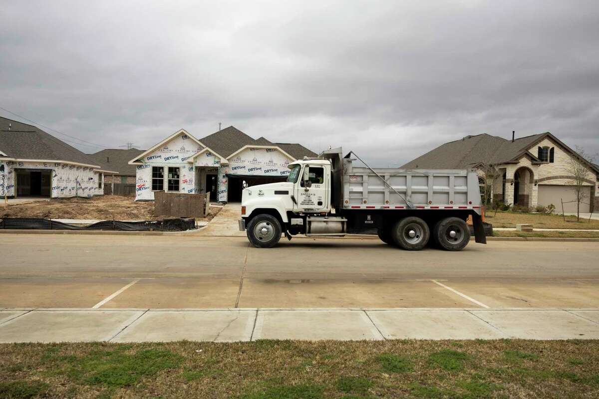 A work truck passes by newly constructed homes in a new development called Raleigh Creek, Saturday, Jan. 30, 2021, in Tomball.