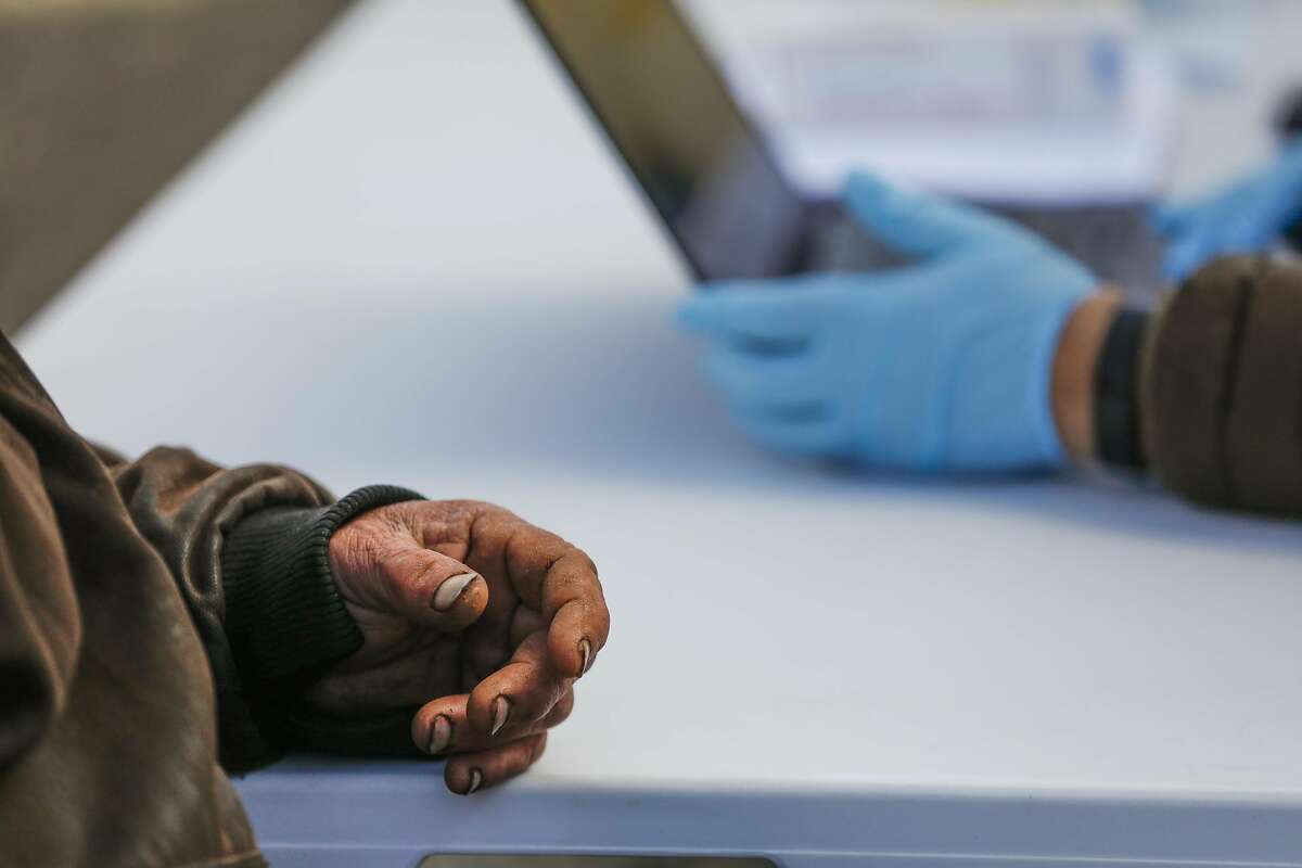 Homeless man Robert Clayton Kerfoot ,57 (left) speaks with Christina Ramirez (right) as he prepares to receive his COVID-19 vaccine from a mobile clinic on Monday, March 15, 2021 in Martinez, California.