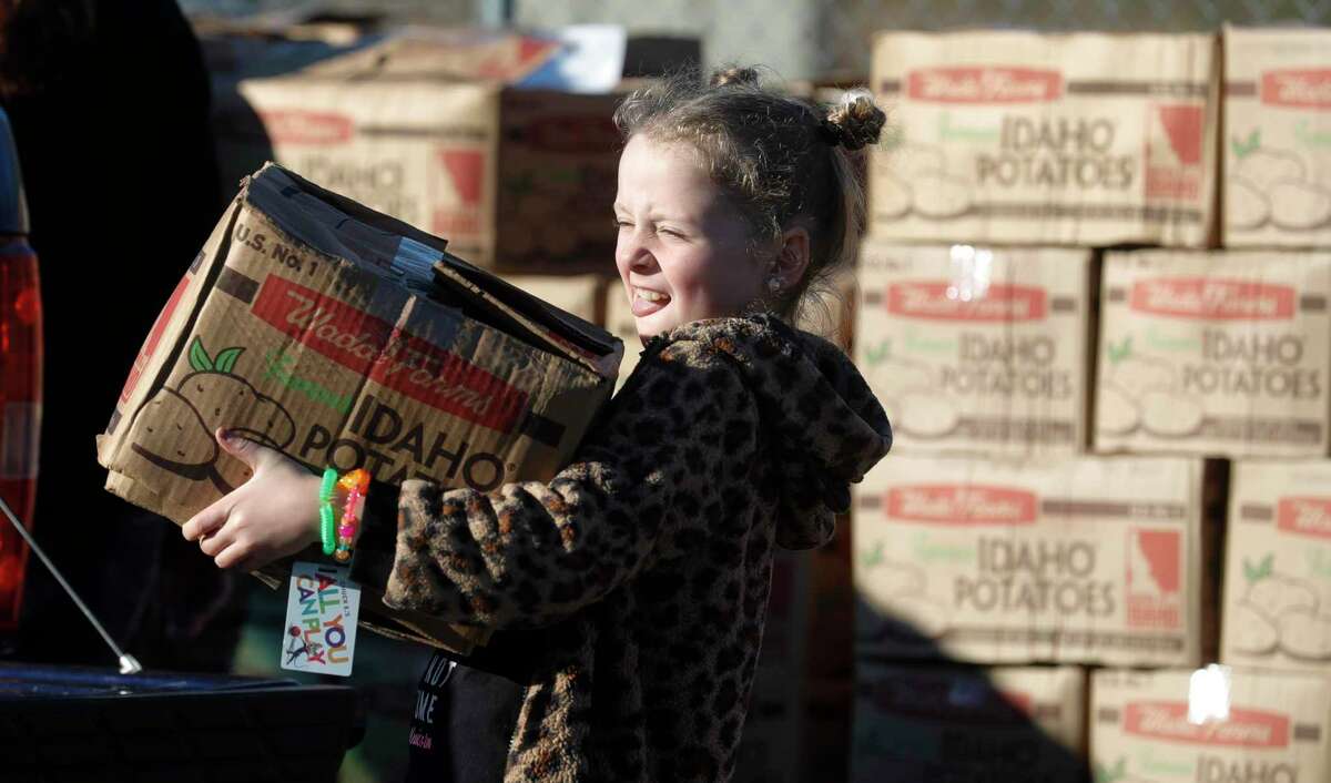 Volunteer Avery Giles carries a box of potatoes to a truck during a mobile food distribution at the East Texas Dream Center, Friday, March 19, 2021, in Splendora. Volunteers handed out food for 200 families.