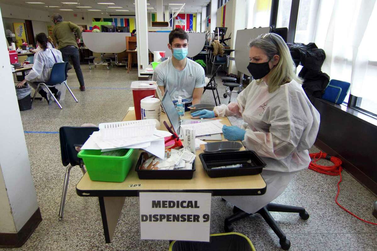 Liz Cavo, RN, prepares to administer the Moderna COVID-19 vaccination to Danbury teacher Ryan Mingachos at a vaccine clinic at Rogers Park Middle School in Danbury, Conn., on Saturday Mar. 6, 2021. Over 900 teachers and staff received the Moderna vaccine during the two-day clinic.