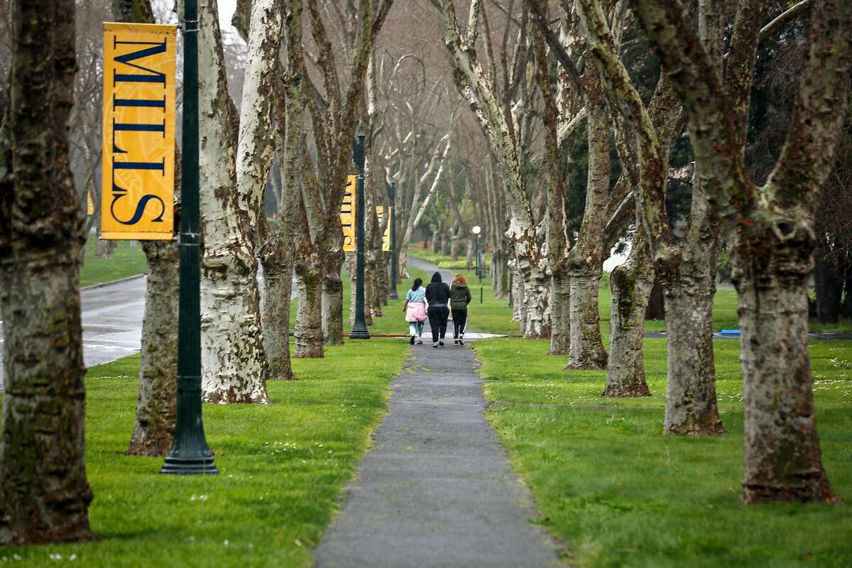 A group of woman walk through the iconic row of trees on Mills College campus on Thursday, March 18, 2021 in Oakland, Calif. One of the oldest and last women's colleges in the country, Oakland's Mills College, is winding down, and is no longer enrolling first-year students.