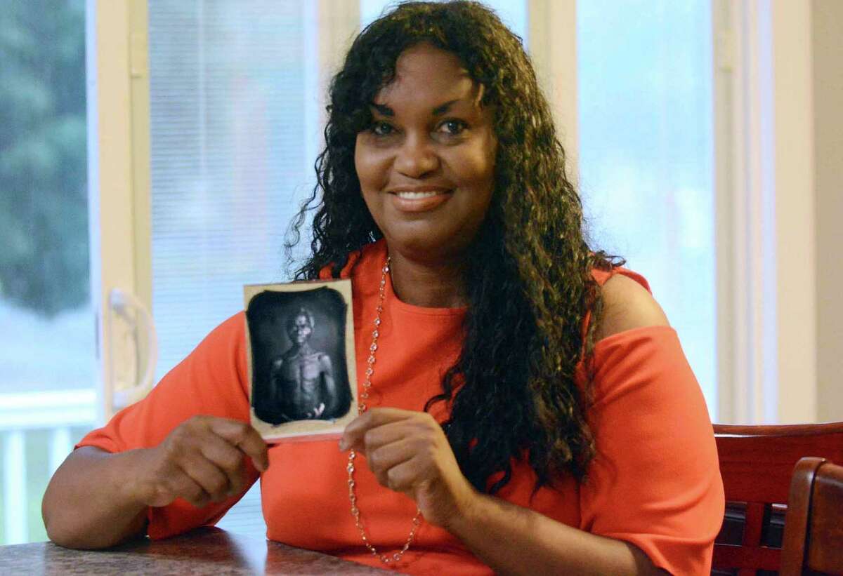 In this July 17, 2018, photo, Tamara Lanier holds an 1850 photograph of Renty, a South Carolina slave who Lanier said is her family's patriarch, at her home in Norwich. The portrait was commissioned by Harvard biologist Louis Agassiz, whose ideas were used to support the enslavement of Africans in the United States. Lanier filed a lawsuit on Wednesday, March 20, 2019 in Massachusetts state court, demanding that Harvard turn over the photo and pay damages.